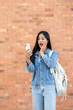 © bongkarn - An amazed Asian female college student looking at her smartphone screen with a surprised expression.