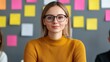 © Rose on Lens - A young woman with glasses smiles confidently in front of colorful sticky notes, suggesting a creative or collaborative environment.