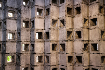 Poster - Close-up of a modern concrete block wall with square cutouts. The texture and pattern are prominent. Architectural Concrete Block Wall with Square Holes: A Modern Design.