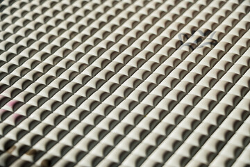 Poster - Close-up of a textured surface with repeating geometric shapes. The pattern is visually interesting and symmetrical. Close-up view of a textured surface matt with repeating shapes
