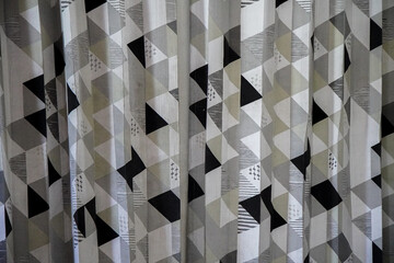 Poster - Close-up of a curtain with an abstract geometric pattern. Triangles in shades of gray and black create a visually appealing design. Geometric Curtain Design.