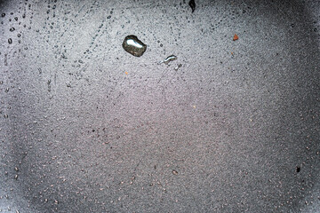 Poster - A detailed close-up reveals the greasy texture of a used frying pan's surface. Oil droplets and residue are visible, showcasing its post-cooking state. Close-up of a Greasy Frying Pan Surface Texture.