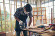 © aFotostock - DIY craftsperson asian man working wood heap carpenter objects woodwork desk. Architect man hands use ruler measure hammer home improvement. Wooden builder carpenter repairing construction workshop