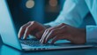 © warunthorn - Hands Typing on Laptop Keyboard in Dimly Lit Environment at Night