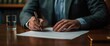 © warunthorn - Businessman Signing Document with Pen on Wooden Desk in Office