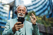 © Jelena Stanojkovic - Business, mature man and music on headphones in city for morning commute, listening to audio playlist. Mature, professional and walking in urban town with radio, streaming song or travel in road.