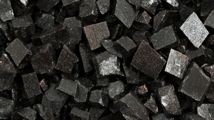 Poster - Textured close-up of black synthetic polyester chunks showcasing their geometric shapes and glossy surfaces ideal for industrial or design applications