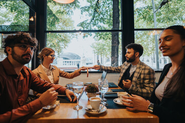 Business colleagues engage in a casual meeting at a cafe table. They are exchanging ideas, enjoying coffee, and using digital devices, fostering teamwork and communication in an informal environment.