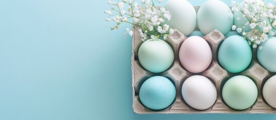 Aufkleber - Pastel Colored Easter Eggs in Carton with Flowers Top View Minimal Celebration Concept Colorful Dyed Chicken Eggs on Blue Background