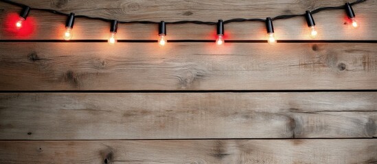 Poster - Festive Christmas lights and decorations elegantly arranged on a rustic wooden background for a warm holiday ambiance