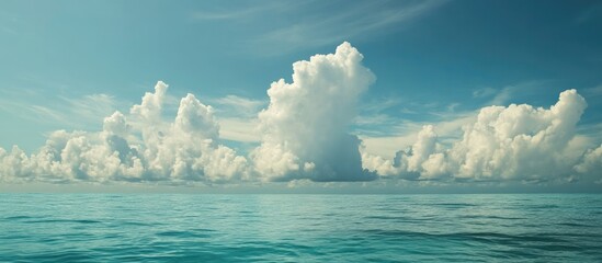Aufkleber - Serene azure ocean with fluffy ivory clouds under a bright blue sky creating a peaceful coastal landscape scene.