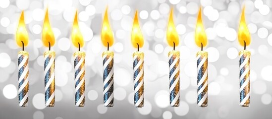Poster - Burning golden candles with blue and white stripes on a shimmering silver backdrop creating a modern festive atmosphere