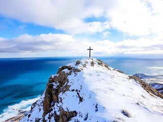 Wall Mural - A cross on top of a snowy mountain overlooking the ocean