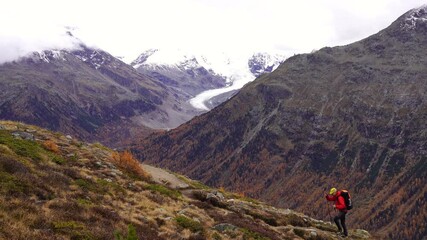 Fototapete - A man hiking in the mountains above Pontresina, in autumn.