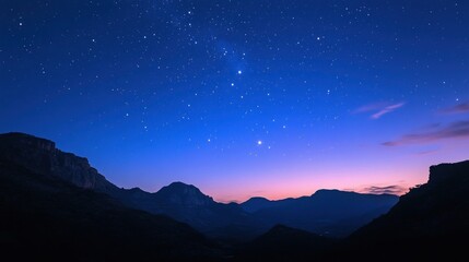 Wall Mural - Starry night sky over silhouetted mountain range at twilight.