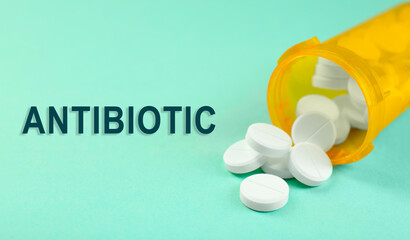 Wall Mural - Bottle of antibiotic pills on aquamarine background, closeup