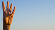 © Akin Ozcan - Hand showing number four gesture on blue sea sky background. Gesturing number 4 index finger. Making number four in sign language. Hand counting four. Space for ad text