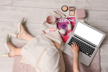 Wall Mural - Female beauty blogger using laptop and makeup products on light wooden floor, top view