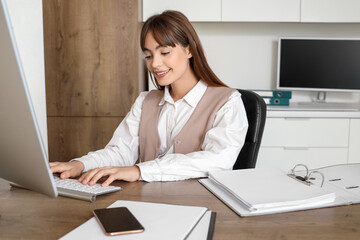 Canvas Print - Young businesswoman working with computer and folder at table in office