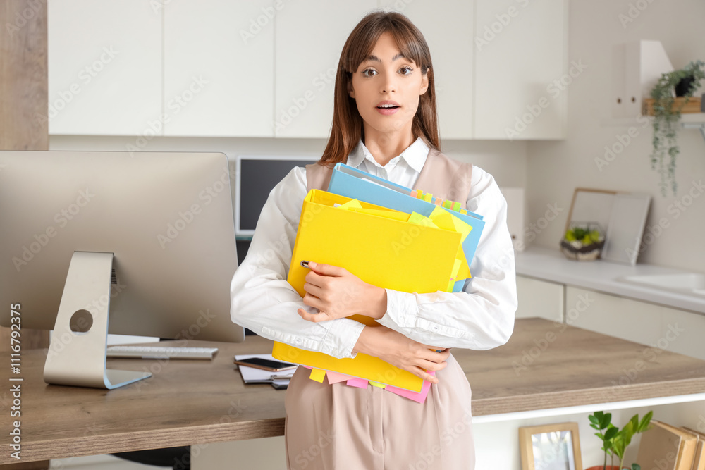 Shocked young businesswoman with folders in office