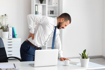 Poster - Young businessman suffering from back pain near table in office