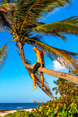 Wall Mural - Man climbing a palm tree on the beach in Mexico.