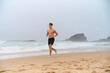 © Микола Бордужак - A young man with an athletic build runs barefoot on the beach. Praia da Ursa. Portugal, 2024. High quality photo