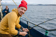 © Julie Meme/Stocksy - A Happy Man in a Red Beanie Fishes From a Boat in the Barents Sea