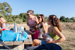 © Raul Navarro/Stocksy - Group of diverse mothers enjoying nature having picnic lunch outdoors