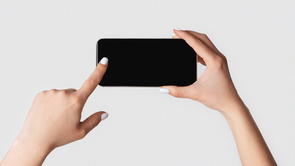 Poster - Closeup view of woman touching mobile phone with blank screen on light background, copy space