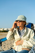 © Tarık Kızılkaya/Stocksy - Senior man sitting at the beach, talking on the phone