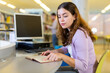 © JackF - Portrait of woman with laptop and book in public library
