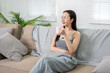 © Wasana - Young woman relaxing on sofa drinking coffee and looking away