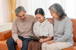 © Verin - cheerful granddaughter playing on digital tablet with grandparent indoors at home,bonding of two generation meeting on holiday time,family lifestyle,relationship