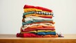© Backdrop Bliss - A neatly folded stack of colorful clothing on a wooden surface, showcasing various fabrics and textures.