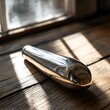 © siyons - Polished metal object on rustic wood, sunlit window background.