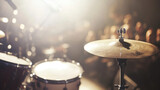 Close-up of a drum set on stage during a live music performance, with a warm ambient spotlight highlighting the cymbals and creating a vibrant atmosphere.