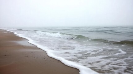 Poster - Misty beach scene with gentle waves lapping the shore, creating a serene atmosphere of nature and tranquility.