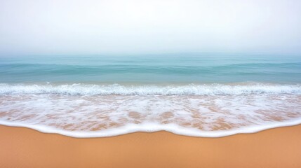 Poster - Serene beach scene with gentle waves lapping at golden sand on a foggy day.