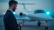 © Photobank - pilot looking at smartphone against background of private jet