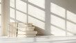 © Steven - A stack of books bathed in soft sunlight, casting gentle shadows against a neutral wall, creating a serene and studious atmosphere.