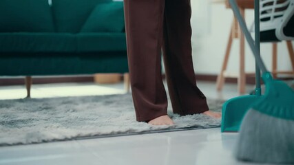 Wall Mural - Housekeeper sweeping dust into a dustpan using a turquoise broom. The scene captures the essence of domestic cleaning and the importance of maintaining a tidy home environment