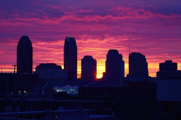 Aufkleber - The sun sets over a bustling city skyline, with tall buildings and urban landscape