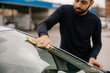 © bugarskipavle3 - Man polishing his car with a microfiber cloth in the driveway.