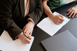 © Seventyfour - Cropped shot of two adult students writing foreign words in dictionaries sitting at desk while studying English in language school, copy space
