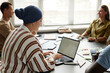 © Seventyfour - Side view of Muslim woman typing on laptop with blank mockup screen while studying sitting at desk in language course group, copy space