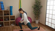 © Krakenimages.com - Woman exercising indoors on yoga mat in gym with asian decor, surrounded by fitness equipment and natural light enhancing the peaceful ambiance.
