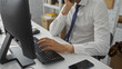 © Krakenimages.com - Young man in office wearing white shirt sitting at desk using computer showing hands typing on keyboard focusing on business tasks indoors reflecting modern workplace vibe