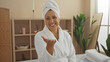 © Krakenimages.com - A beautiful hispanic middle-aged woman in a wellness center, wearing a bathrobe and towel, smiles warmly in an inviting spa interior.