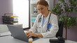 © Krakenimages.com - Female doctor working on a laptop in a modern clinic room, displaying professional focus while surrounded by medical equipment and interior decor.